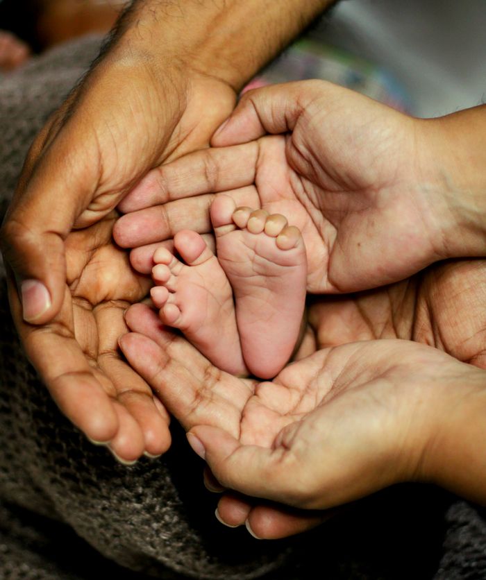 Close-up of adult hands gently holding a baby's feet, symbolizing family care and love.