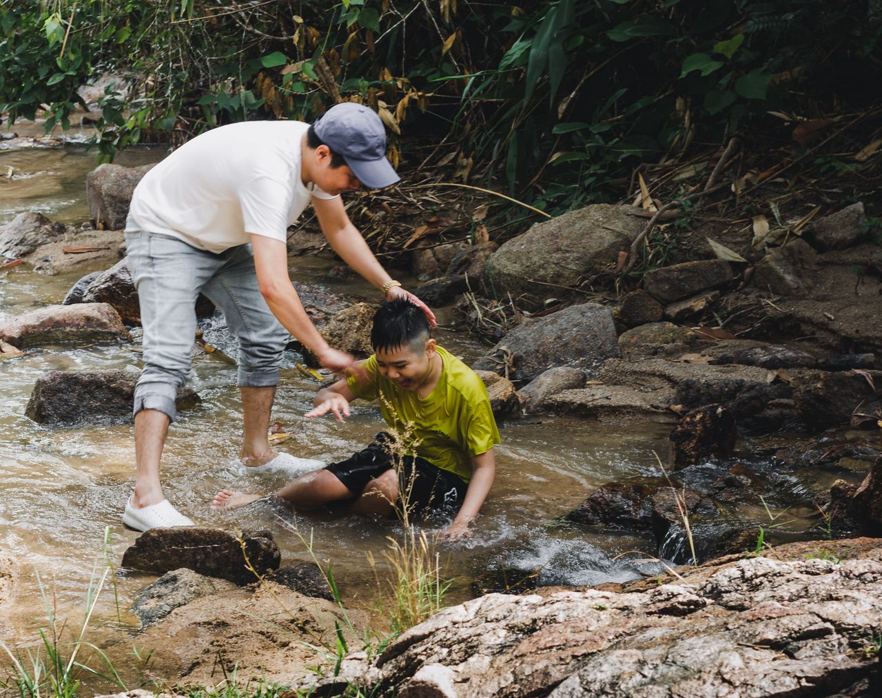 A father helping his son in a creek in Kon Tum, Vietnam, creating bonding moments outdoors.